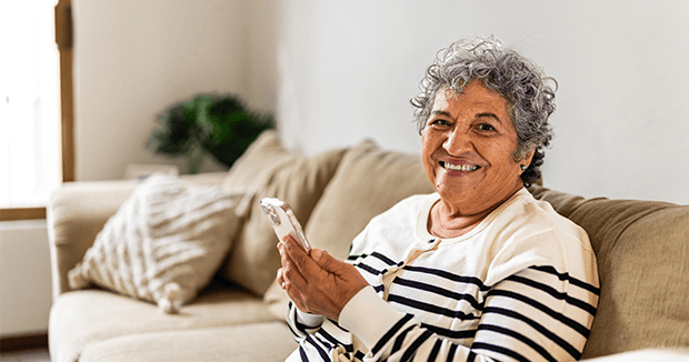 Senior woman smiling while holding a smartphone