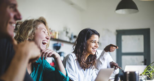 A group of coworkers laughing at a meeting.