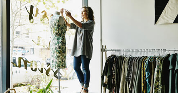 A woman dressing her storefront manequin